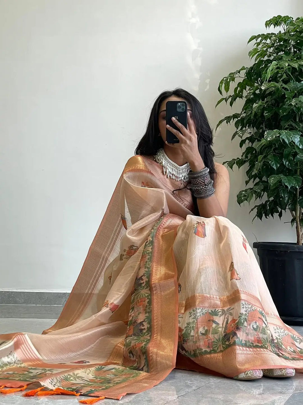 Model seated in Soft Gold Zari Tissue Saree with digital print.
