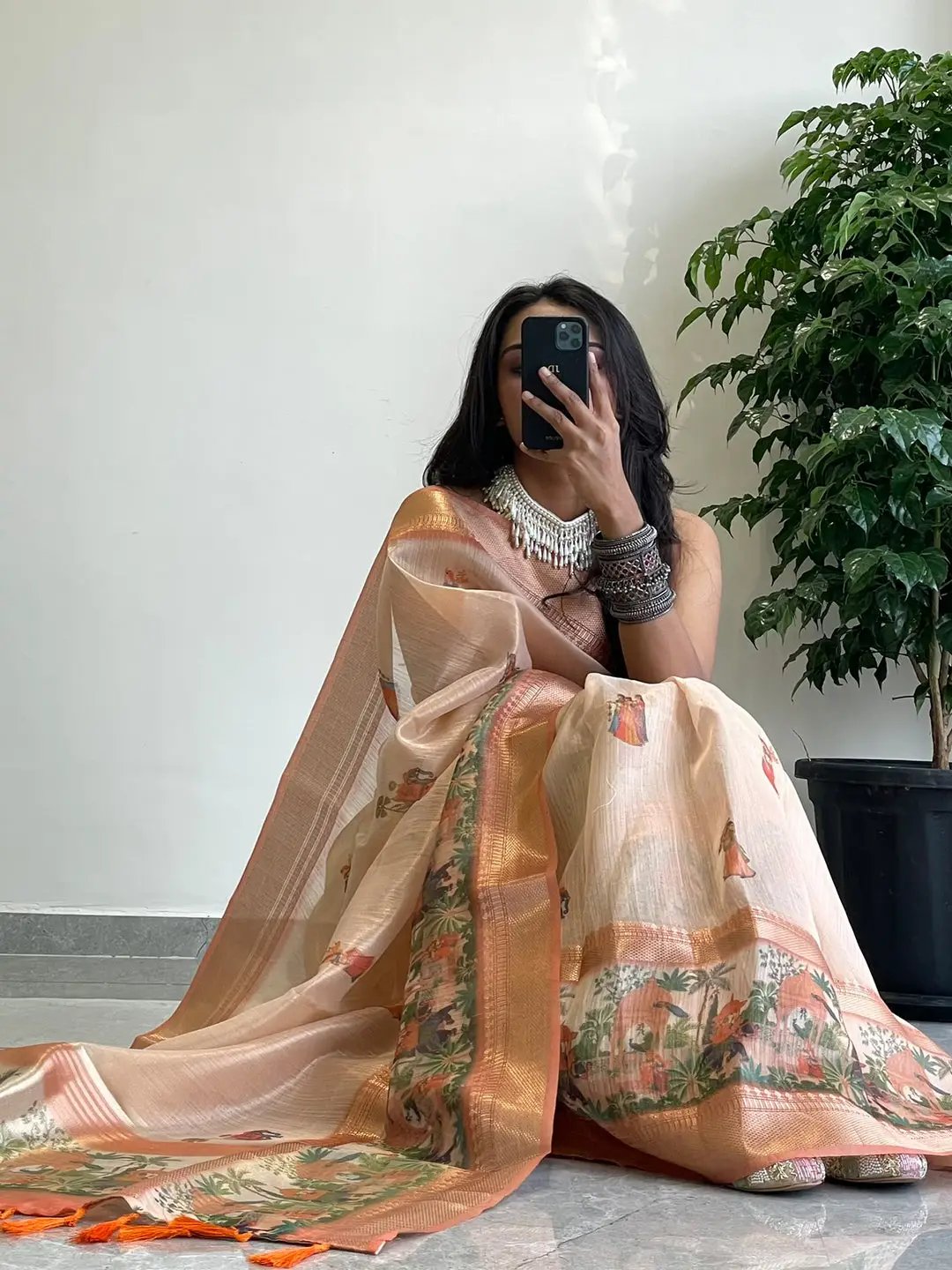 Model seated in Soft Gold Zari Tissue Saree with digital print.