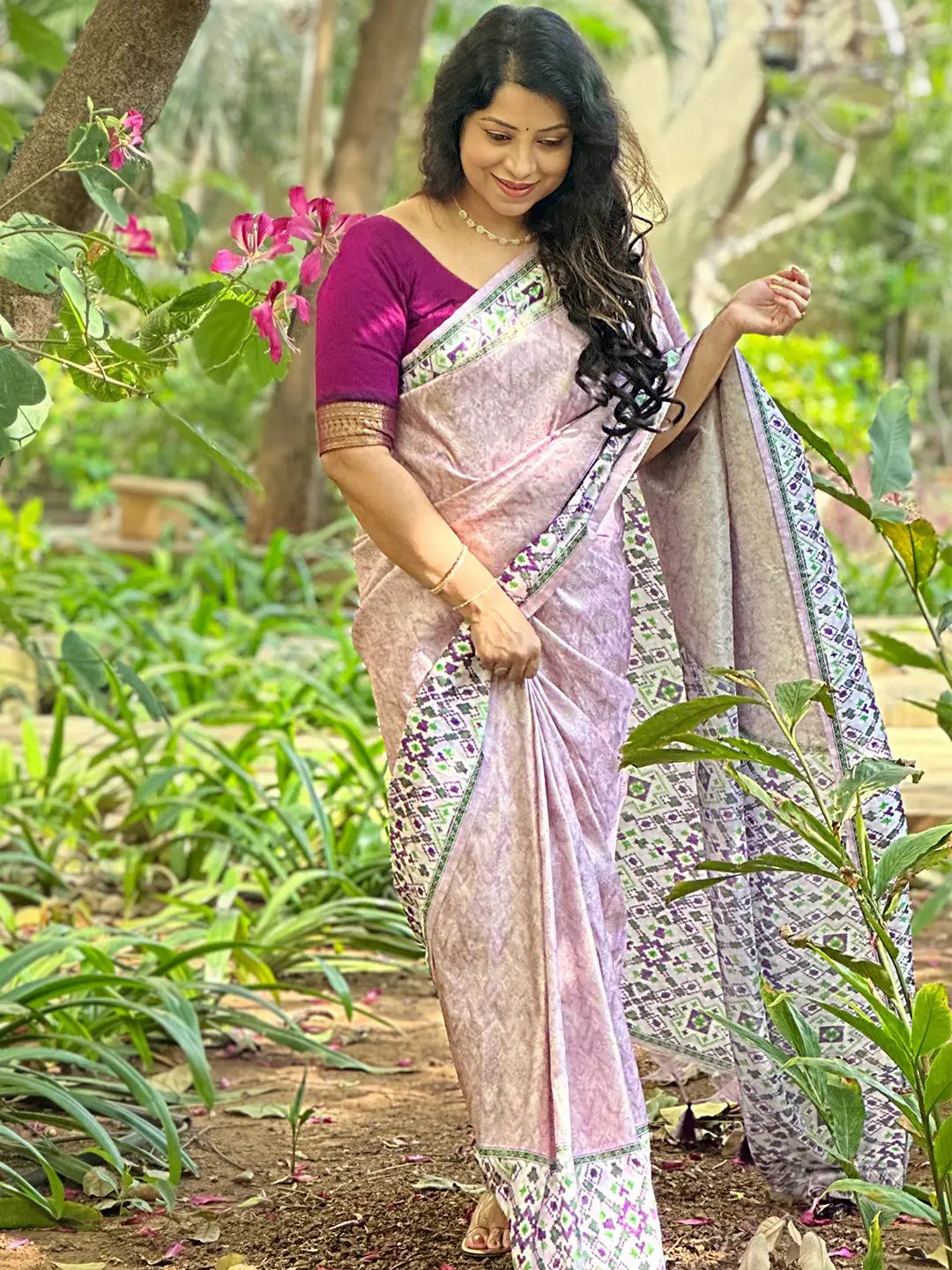 Model posing in pink Patola print Kanjivaram saree in garden