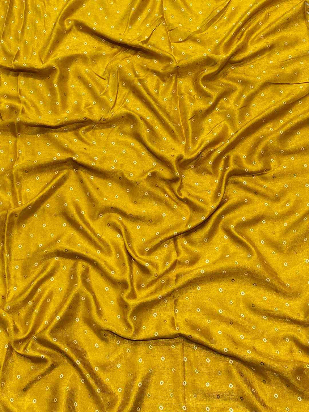 Close-up of yellow Manipuri silk fabric with small foil print dots.