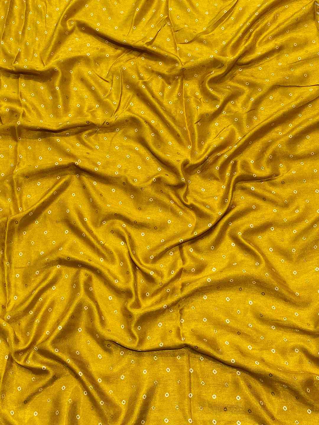 Close-up of yellow Manipuri silk fabric with small foil print dots.