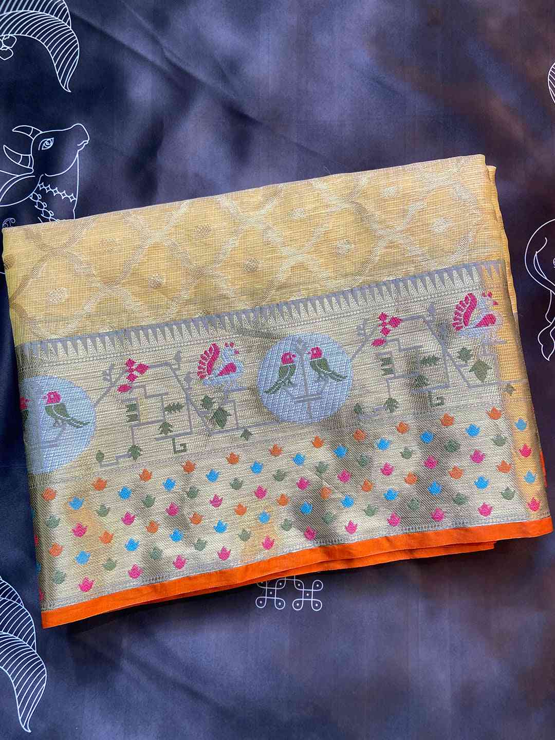 Folded yellow Kota Doria silk saree with colorful Minakari design