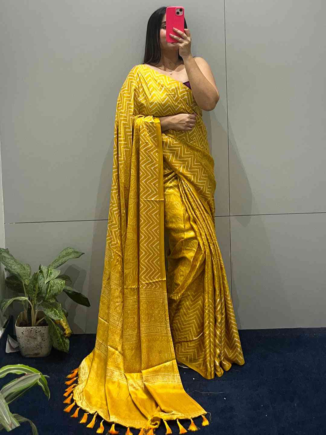 Yellow Manipuri silk saree with foil print, showcased against a plain wall.