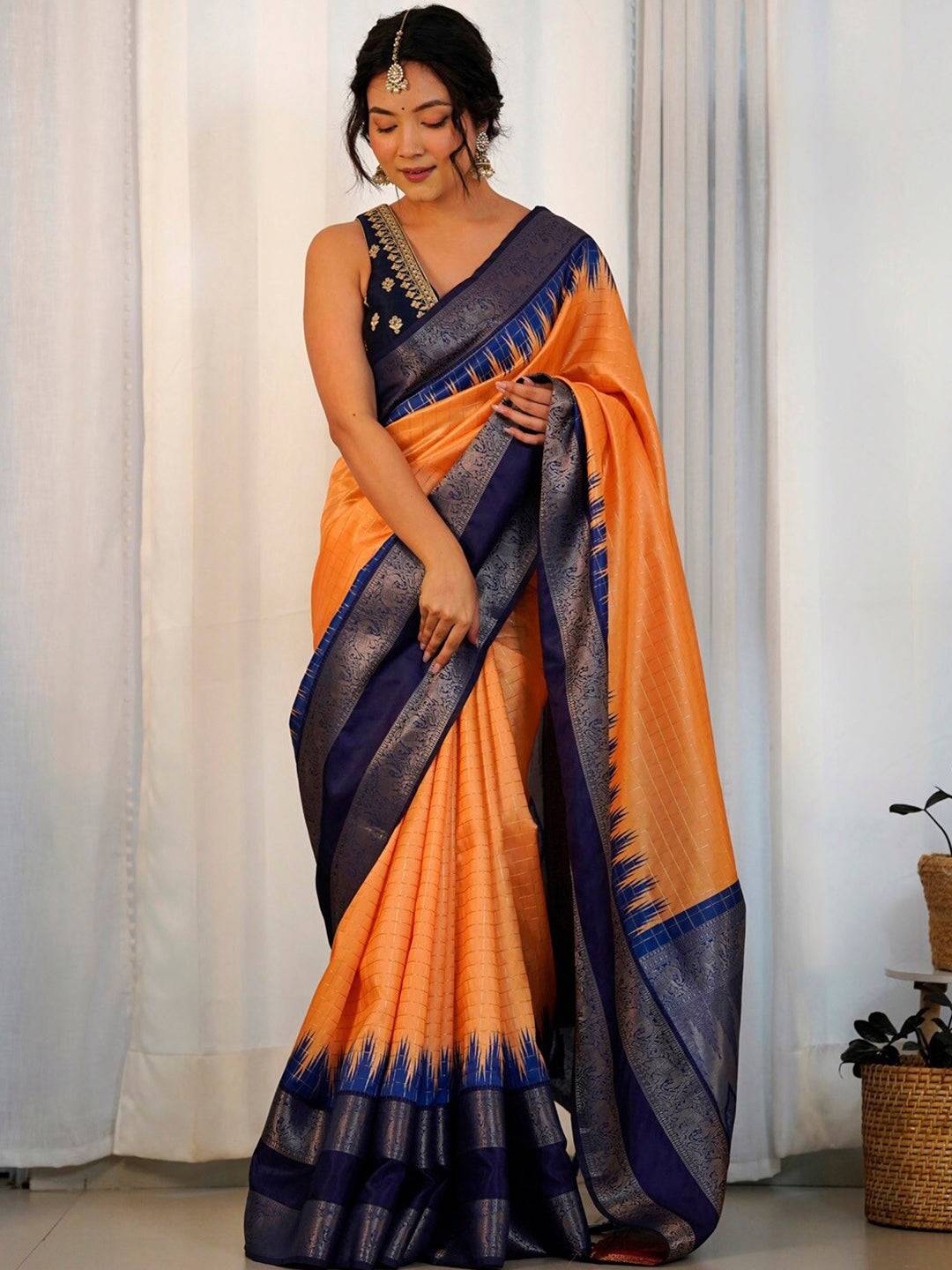 Model wearing orange Banarasi silk saree with blue border.