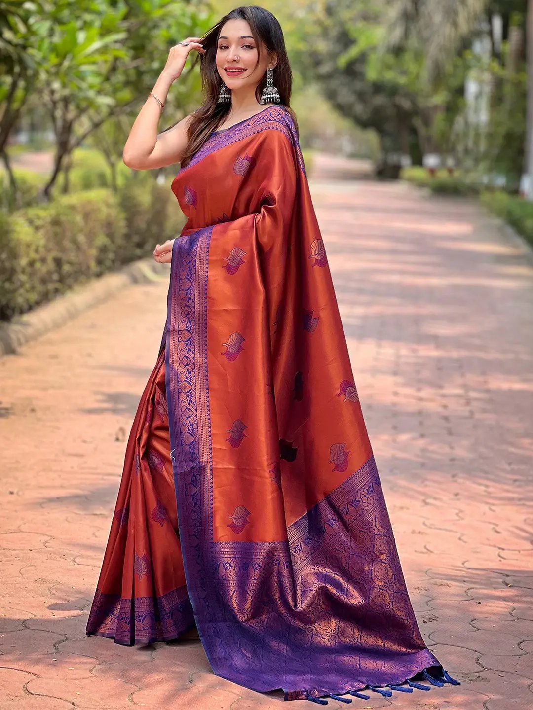Woman in rust red Kanjivaram saree with gold zari weaving.