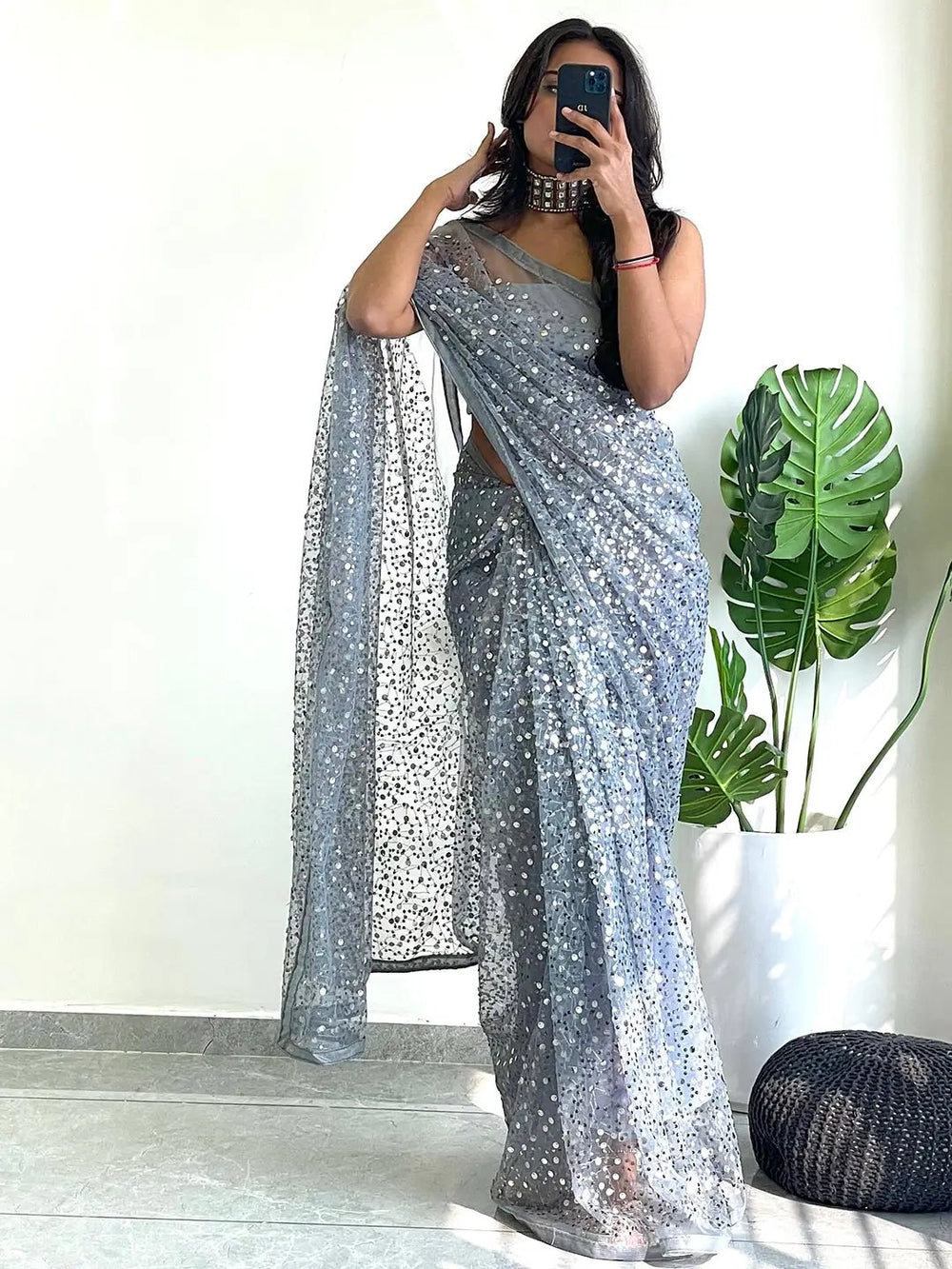 Model posing in a sequined net saree, capturing a selfie.