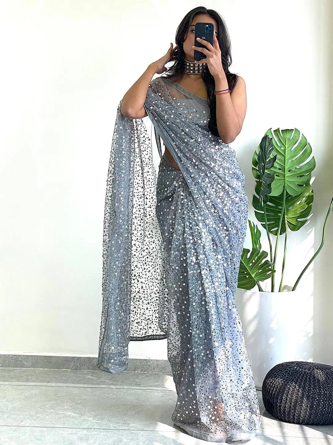 Model posing in a sequined net saree, capturing a selfie.