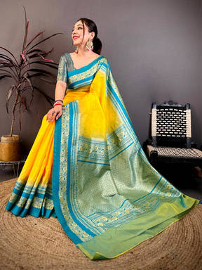Blue and green silk saree with gold zari border, displayed on a floor with a textured rug, traditional attire for celebrations