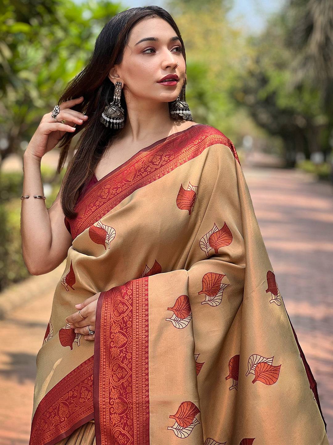 Elegant woman in beige saree with red border and leaf motifs