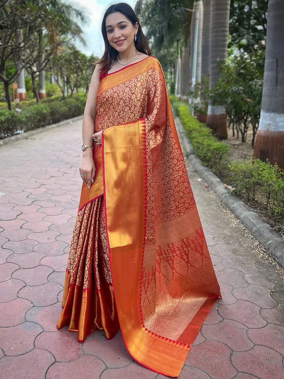 Orange gold tissue saree with jacquard work, worn by a woman.