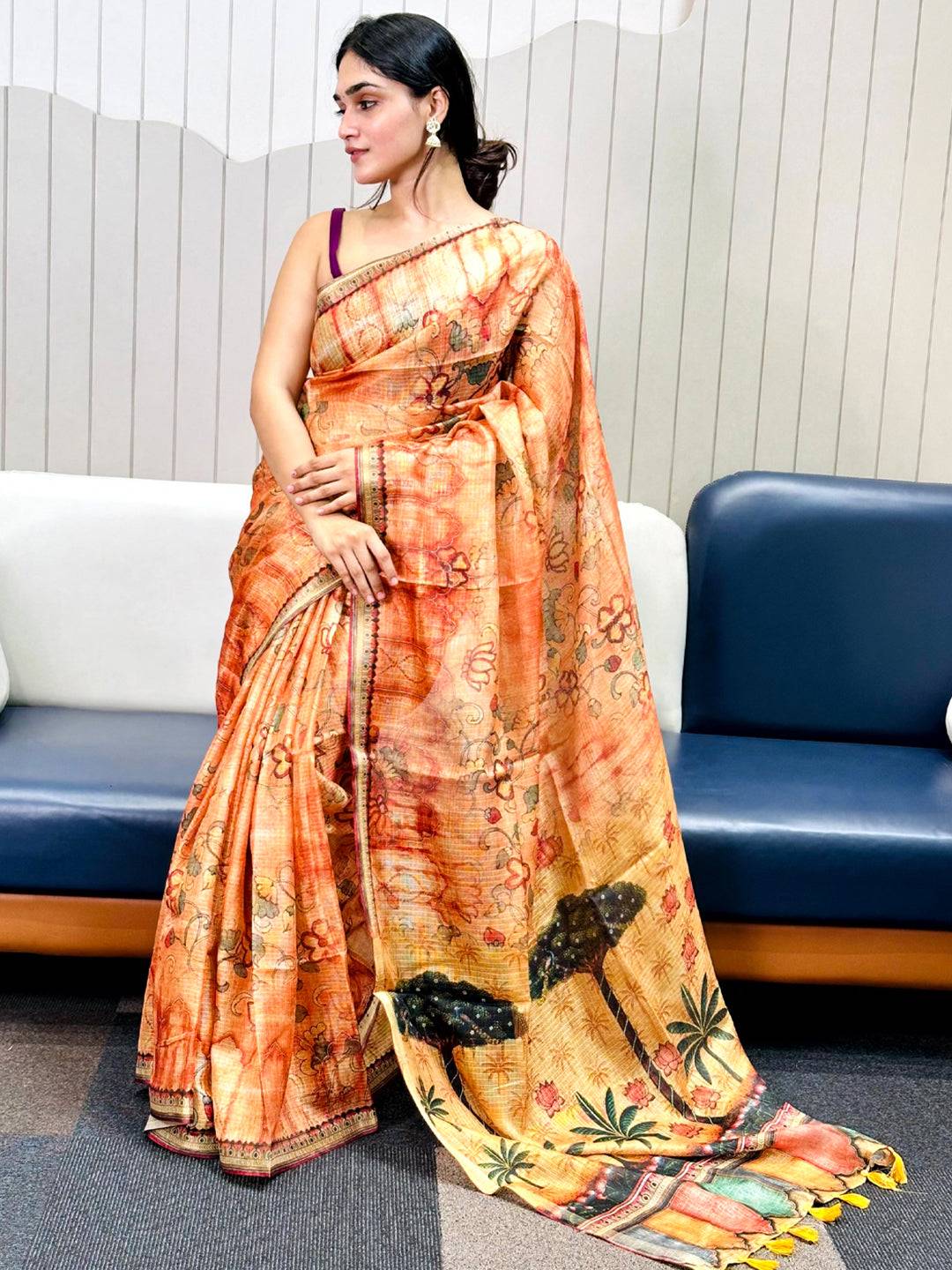 Woman wearing orange Kota Doriya silk saree with floral pattern.
