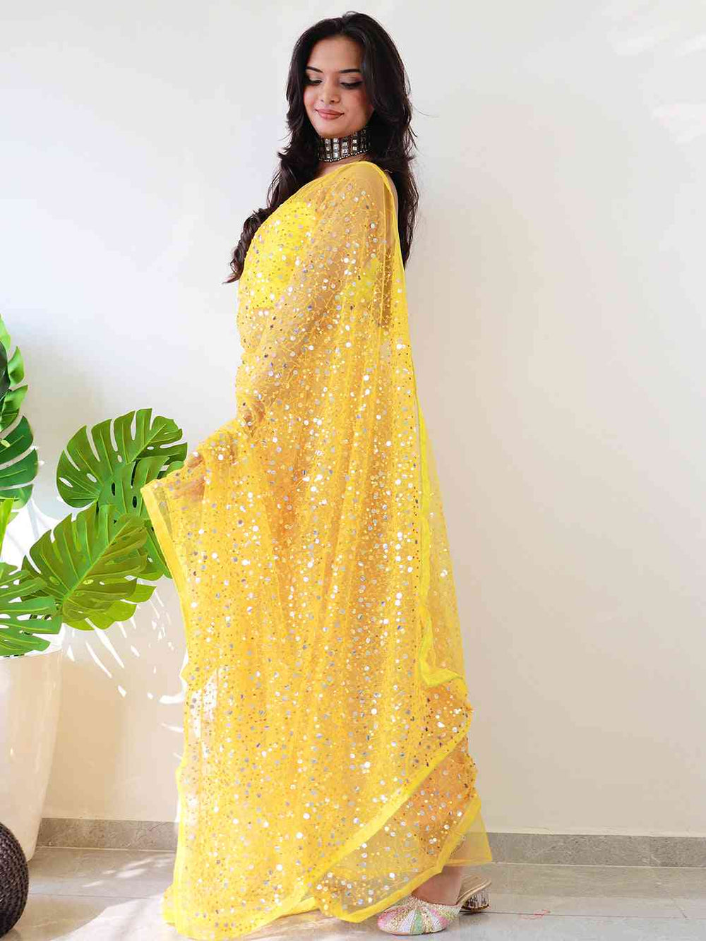 Back view of yellow sequined net saree on model