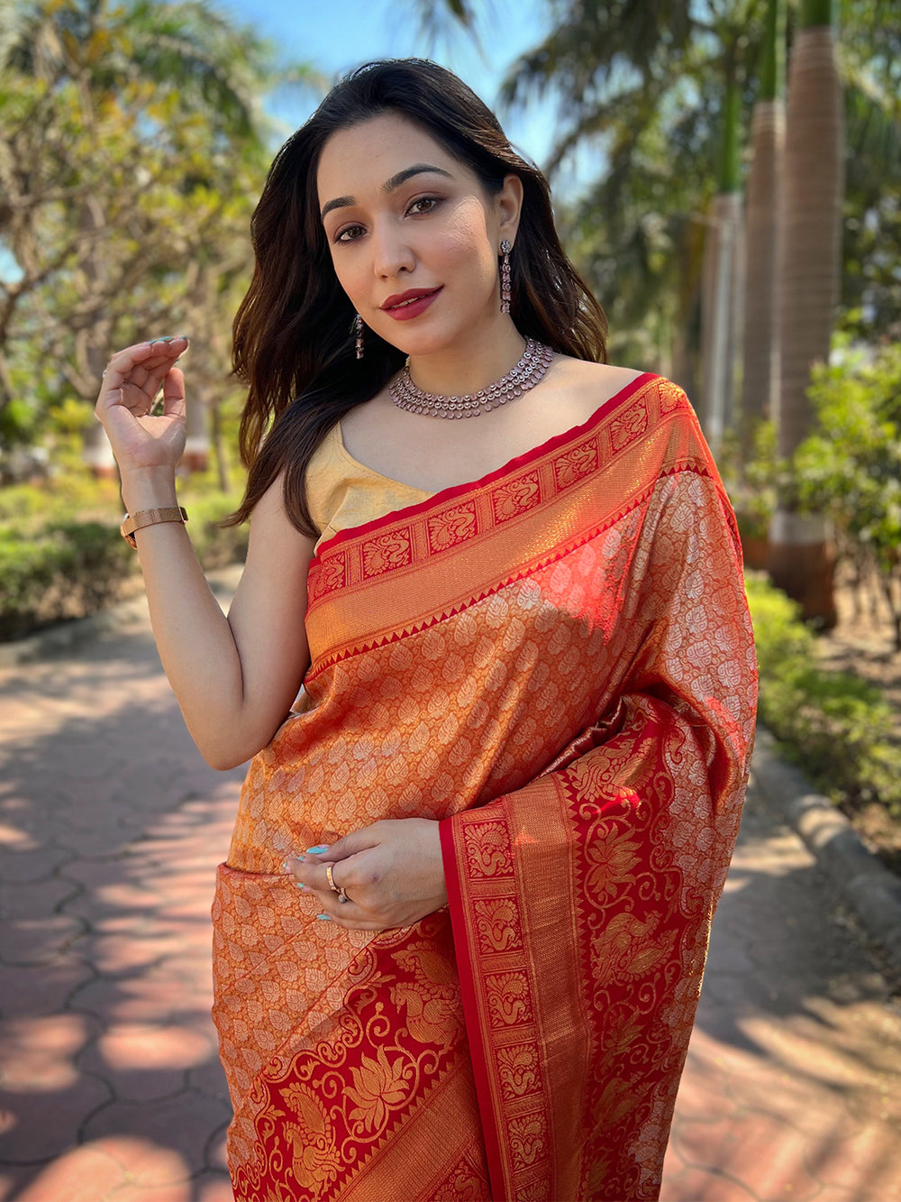 Woman in orange-red Kanjivaram saree with gold border details