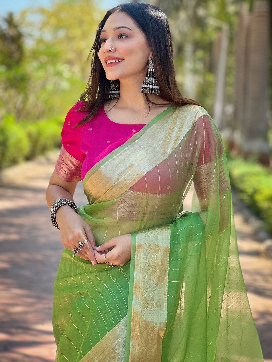 Green organza saree with gold zari border, worn with pink blouse.