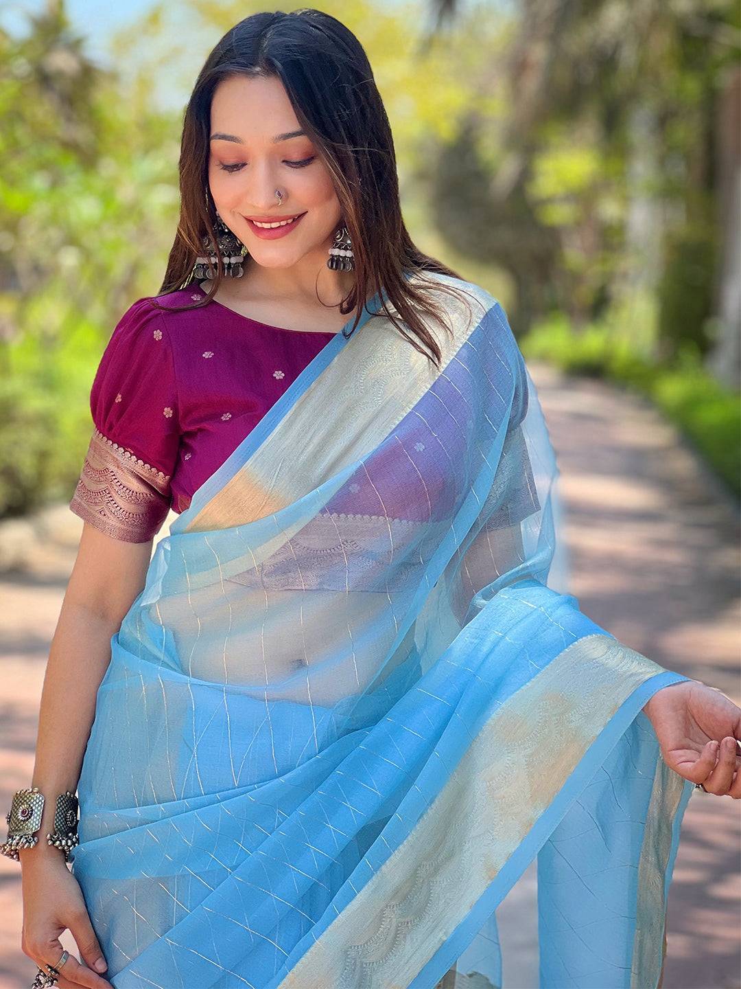 Blue organza saree with gold zari border, worn by a model