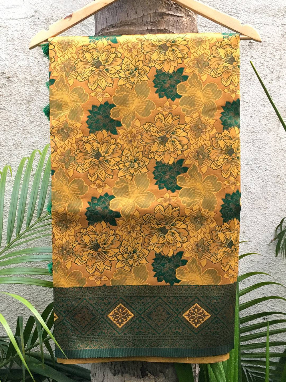 Mustard silk saree with floral butta design displayed on hanger.