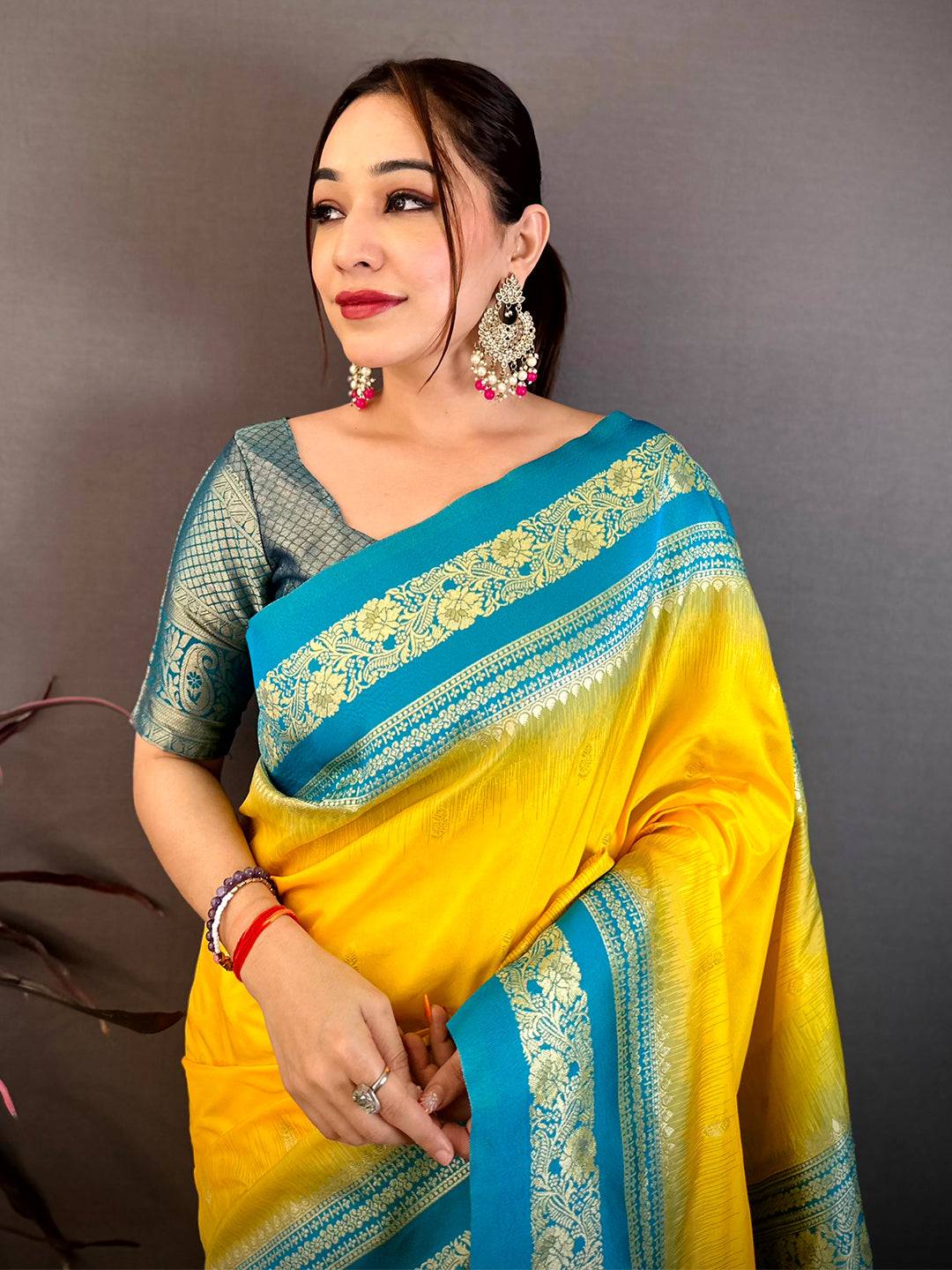 Yellow and blue silk saree with intricate gold zari border, worn by a woman with earrings and bangles, traditional attire for festive occasions