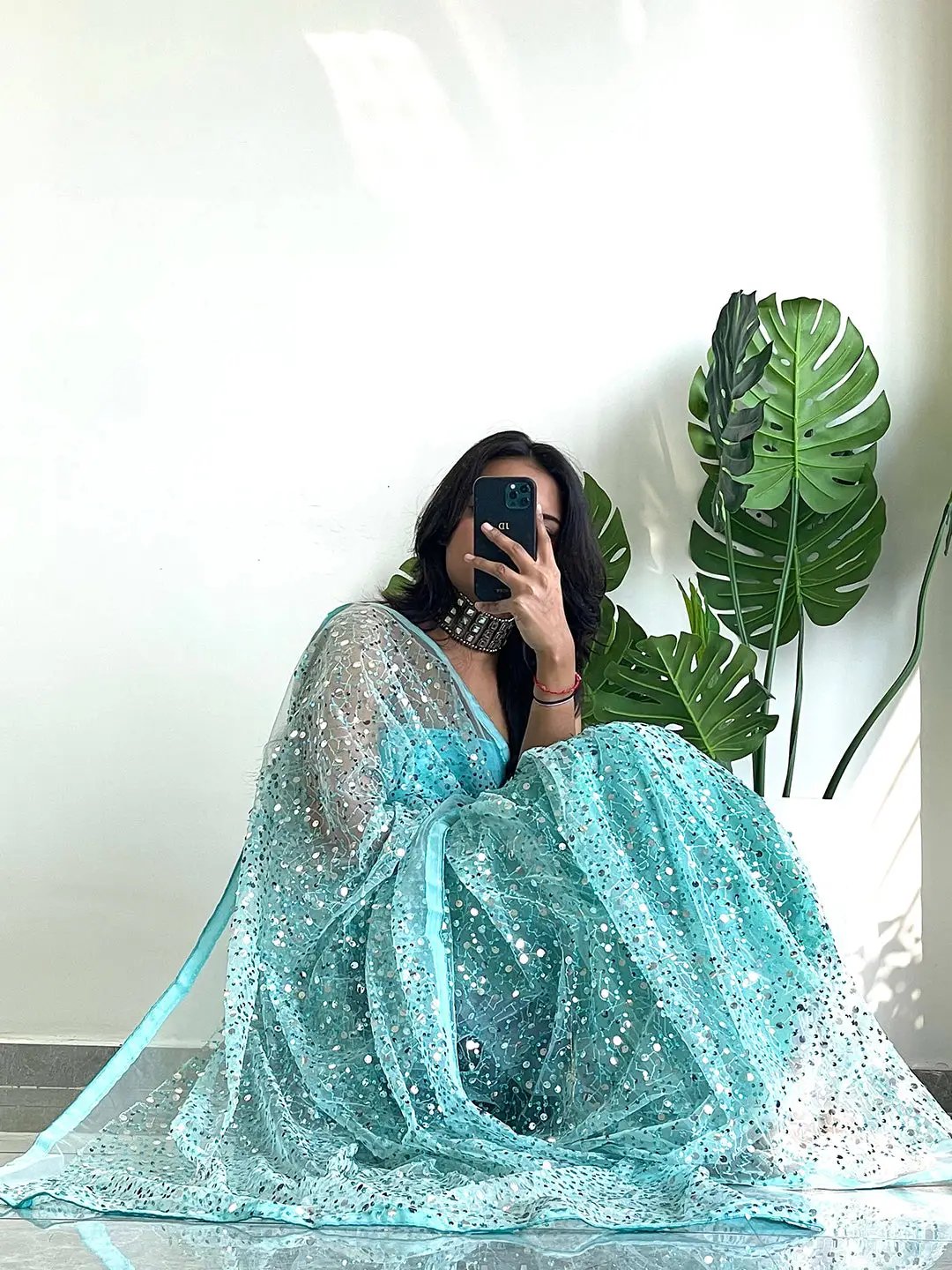 Model seated in net saree with sparkling sequins details