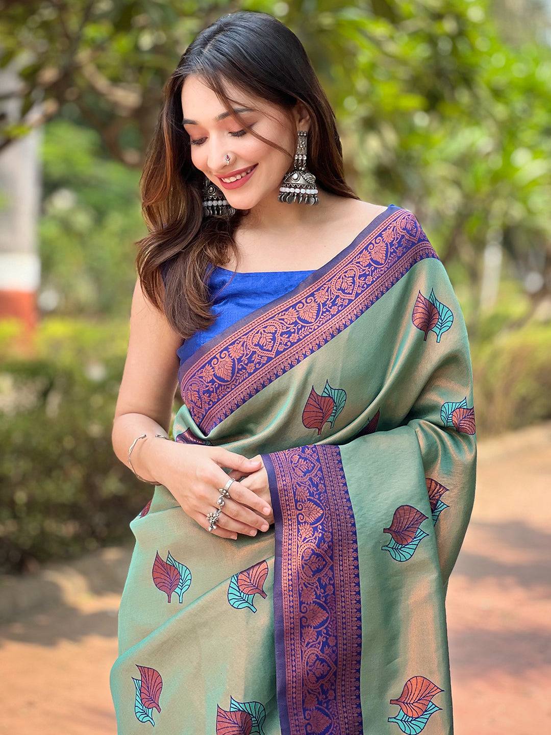 Woman in pista Kanjivaram saree with gold zari weaving, smiling.