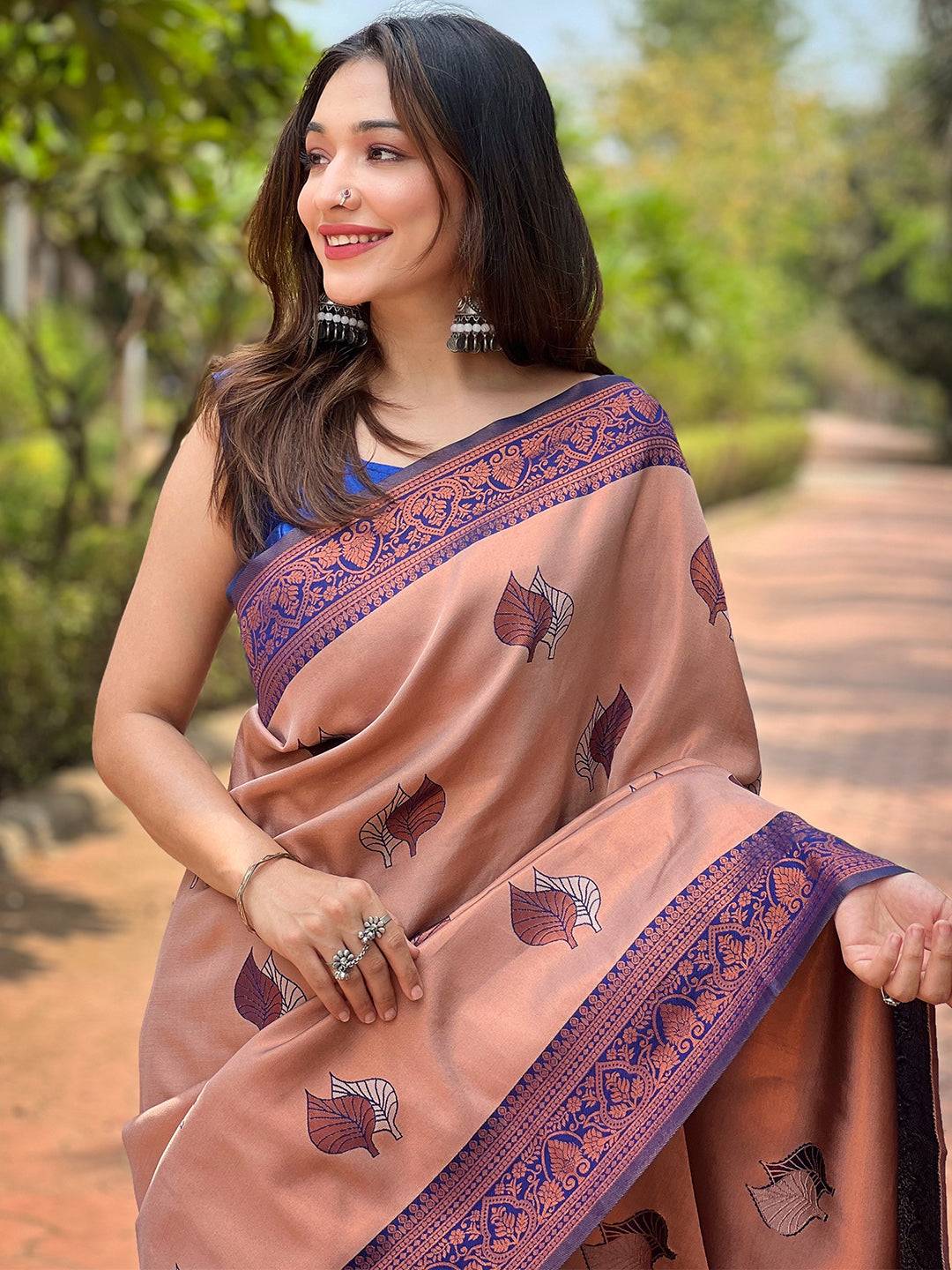 Woman in pastel peach saree with purple border, outdoor setting