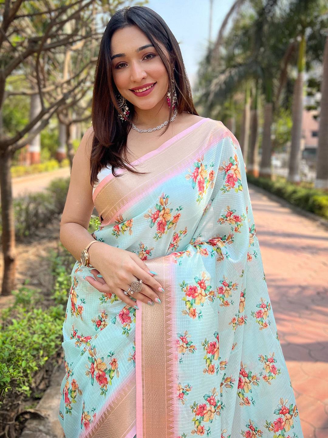 Model smiling in turquoise Kota saree with floral print.
