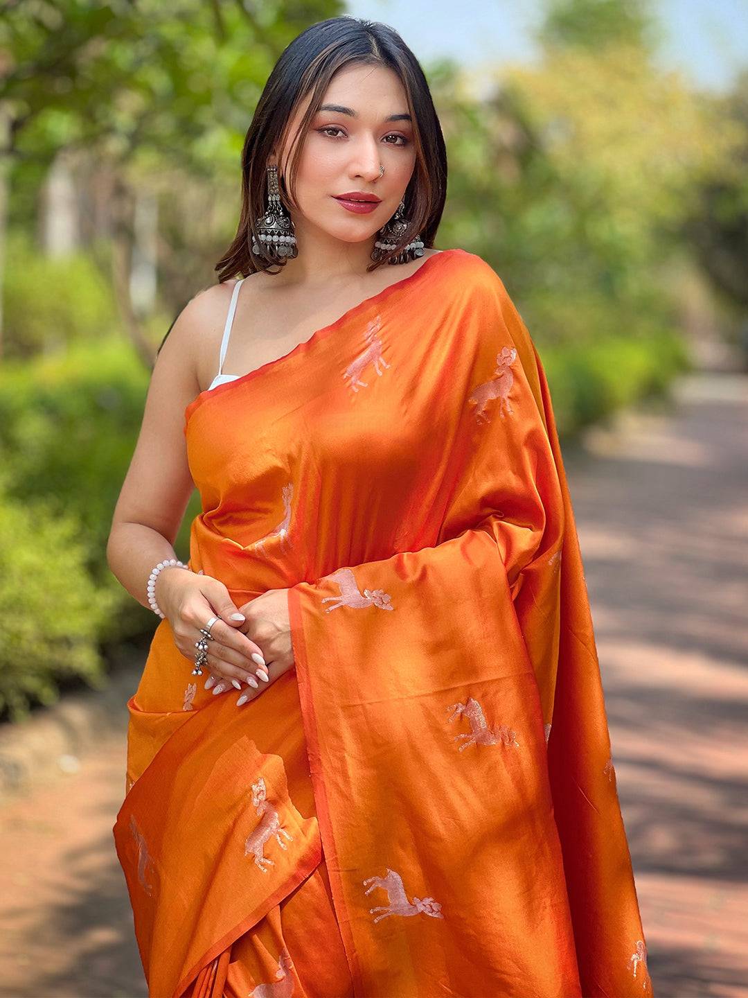 Model wearing orange soft silk saree with zari pallu