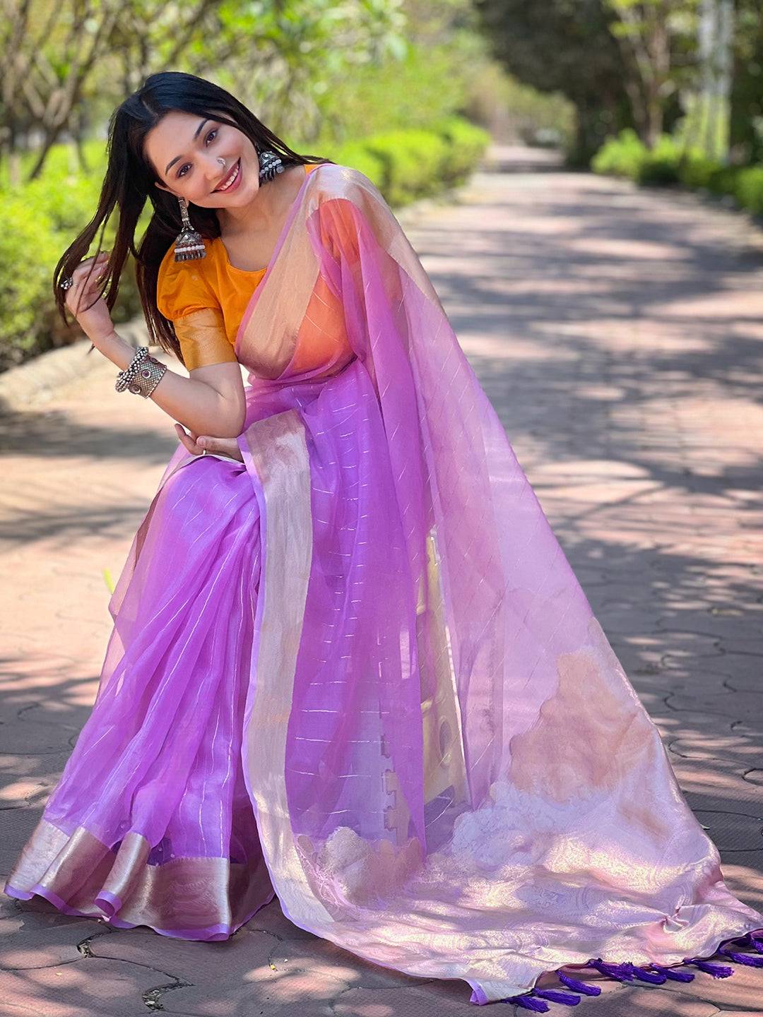 Woman in purple organza saree, showcasing gold zari details
