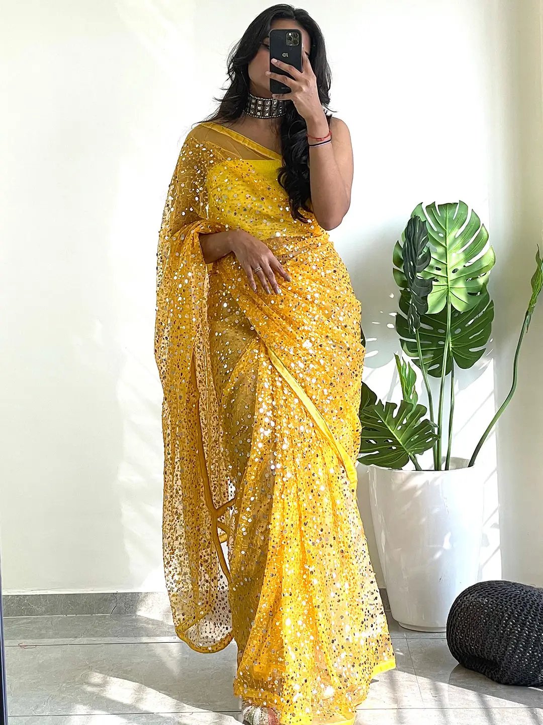 Model taking selfie in yellow sequined net saree