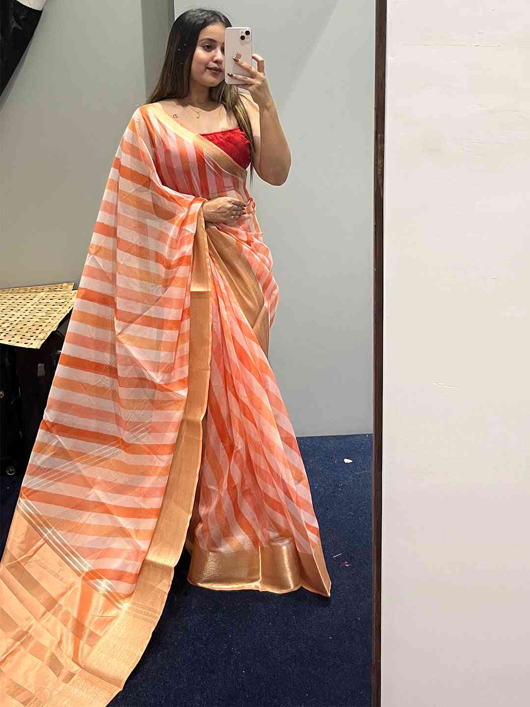 Party wear organza saree with orange leheriya pattern and red blouse.