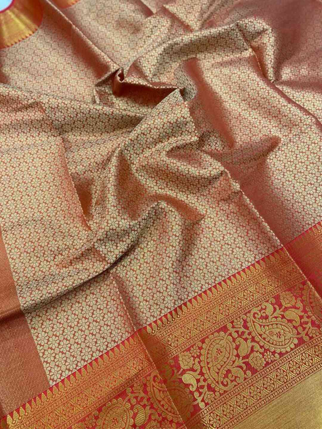Close-up of gold zari Kanjivaaram silk saree fabric with floral design.