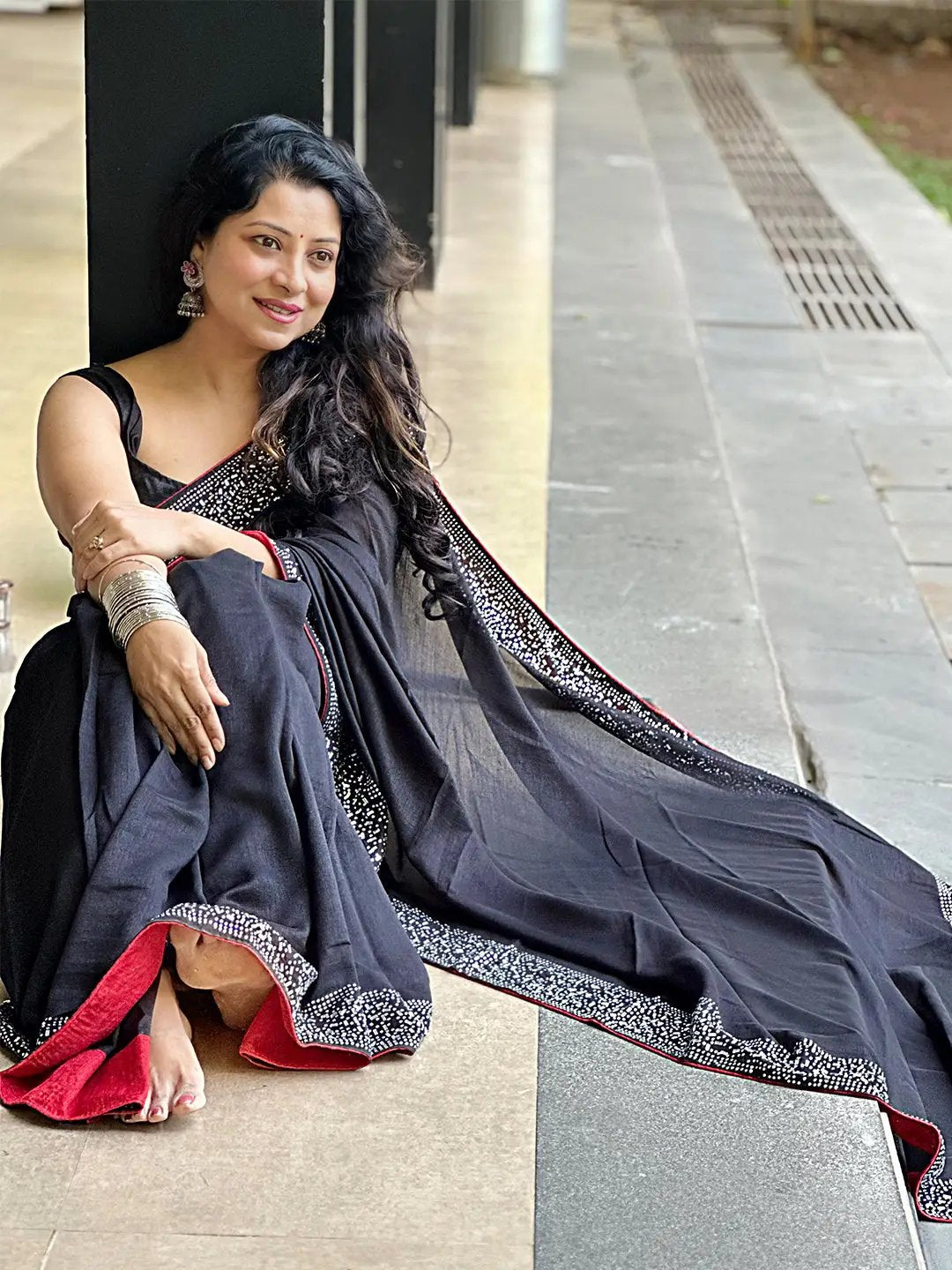Black poly silk saree draped elegantly with red accents