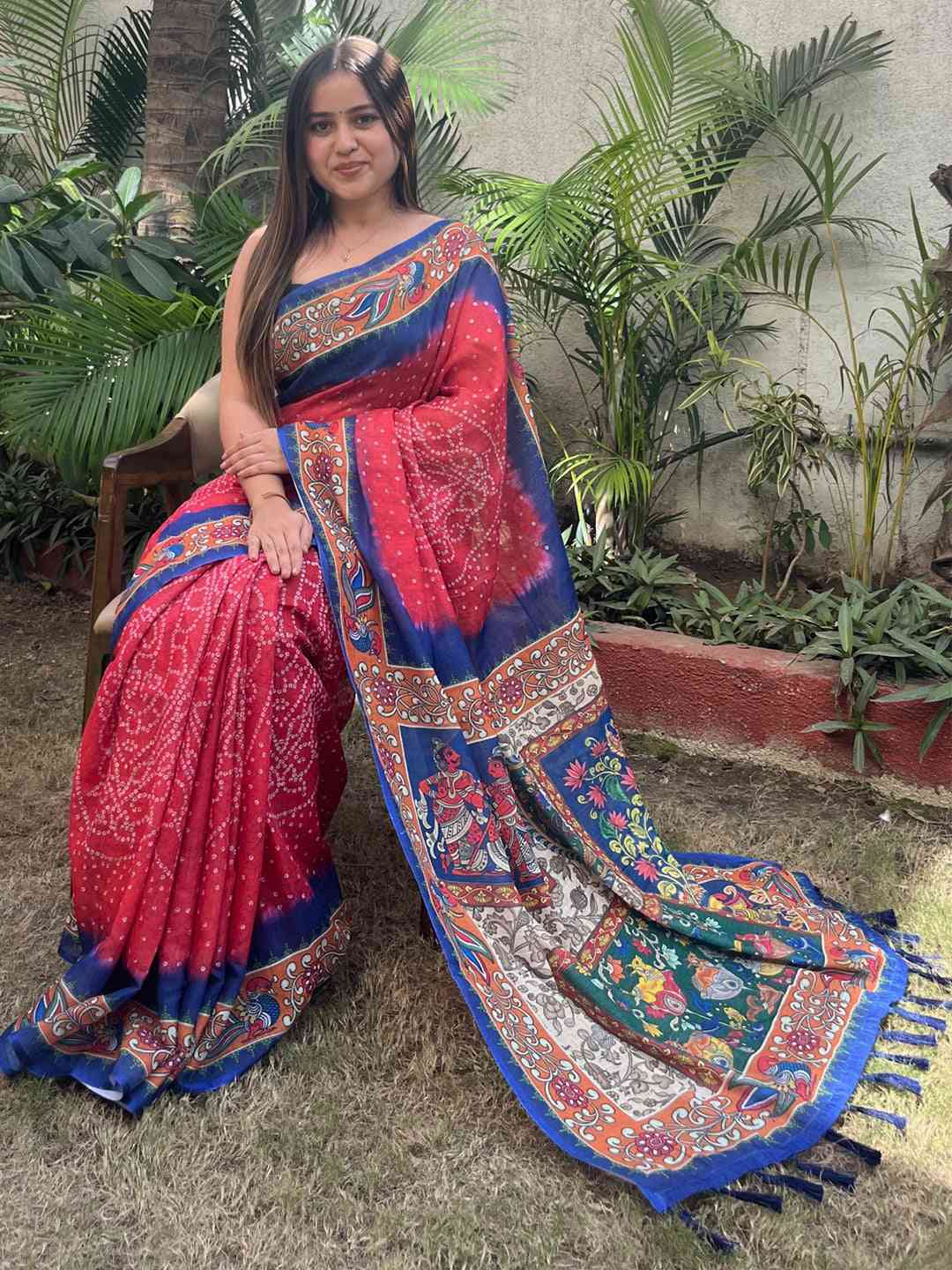 Red linen saree with Bandhej and kalamkari print, seated pose