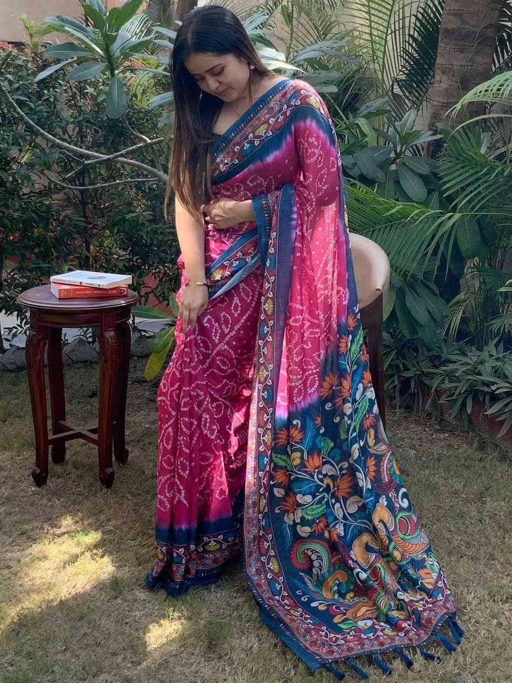 Woman showcasing pink Bandhej Kalamkari Saree in garden