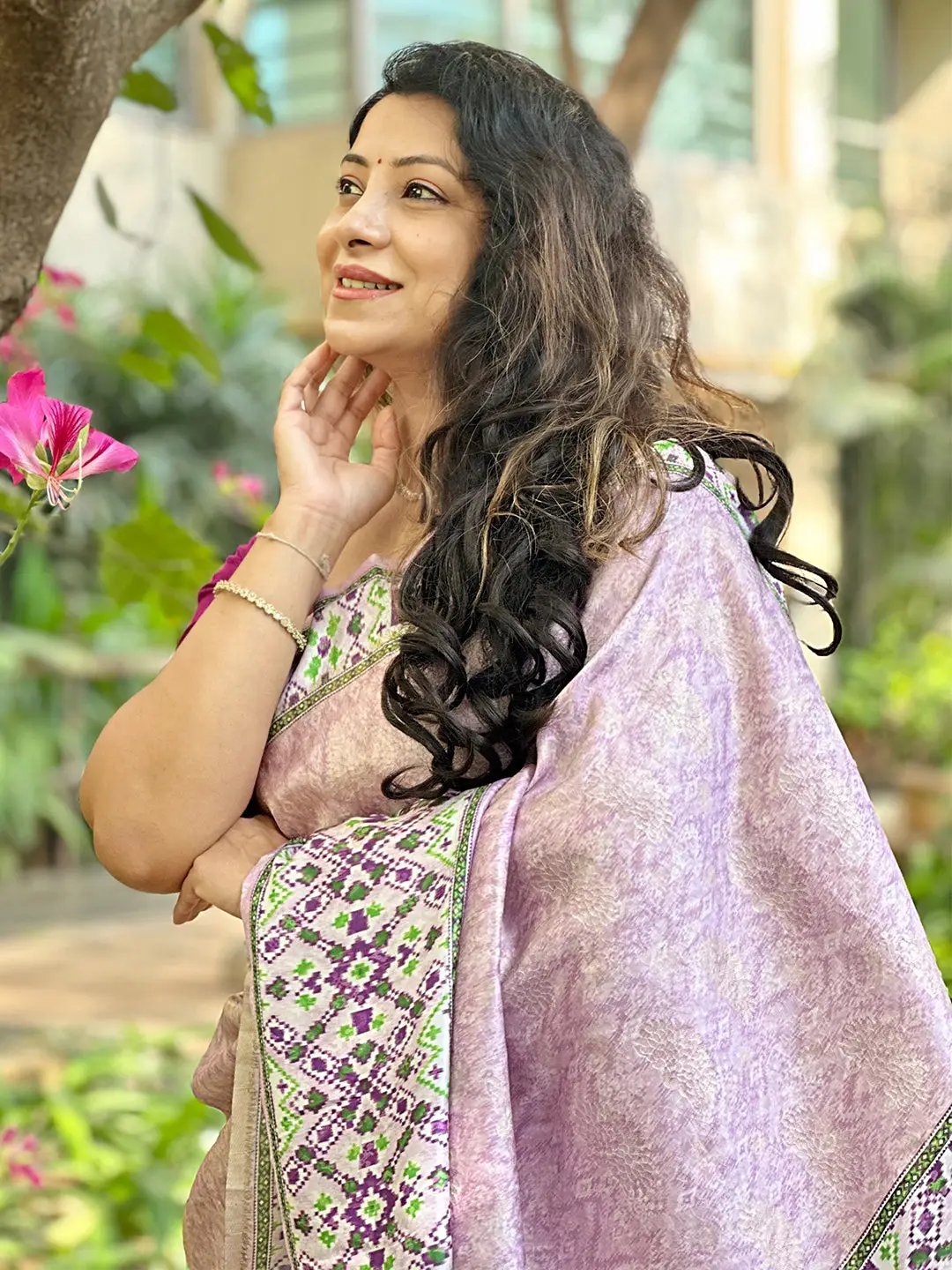 Smiling woman in pink Patola print Kanjivaram saree outdoors