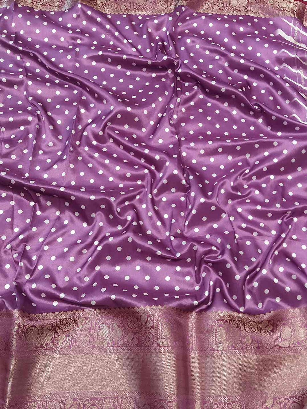 Close-up of purple leheriya saree fabric with polka dots and zari border.