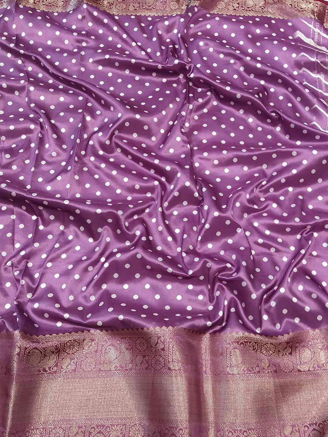 Close-up of purple leheriya saree fabric with polka dots and zari border.