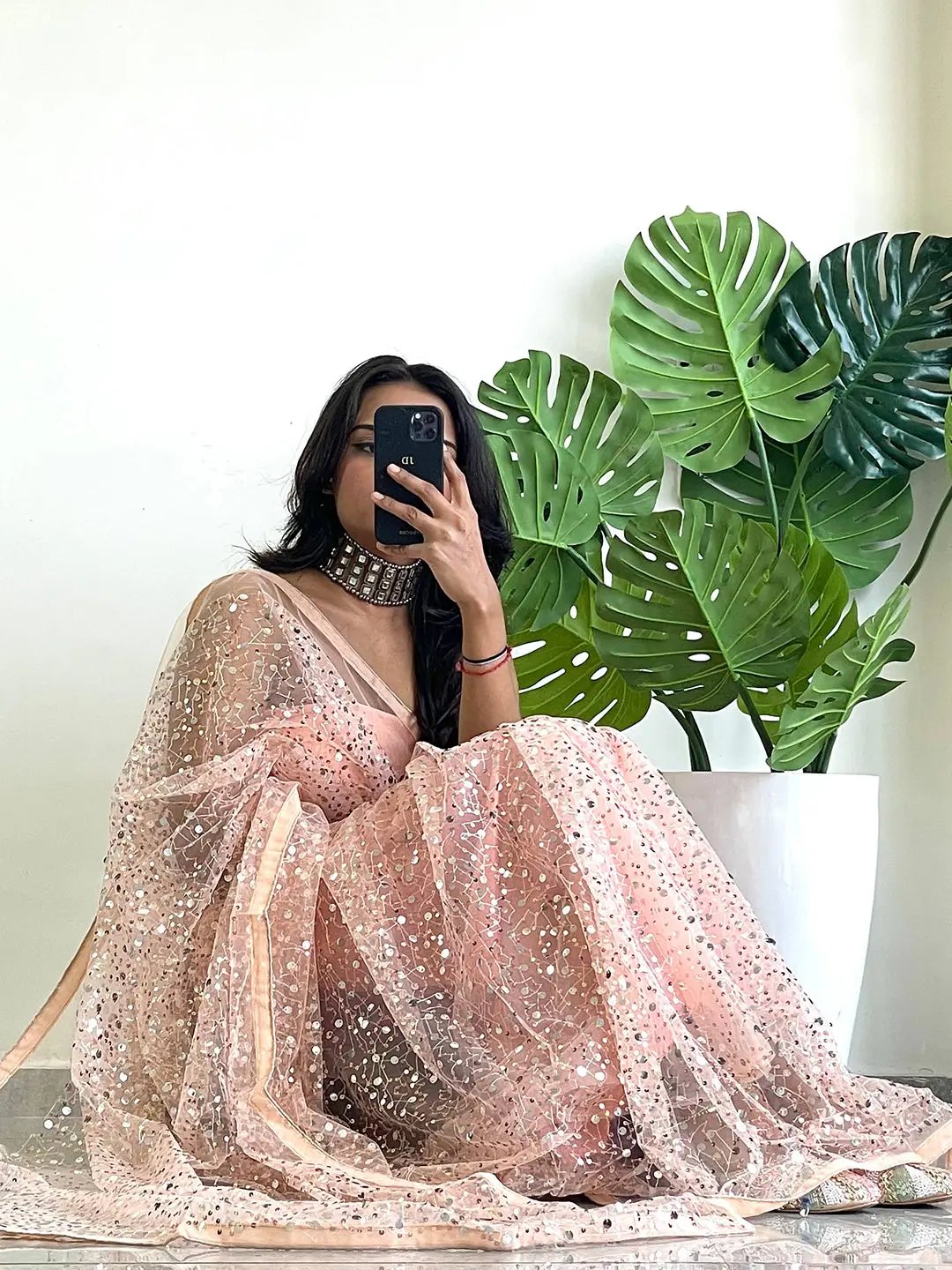 Seated model in net saree with sparkling sequins.