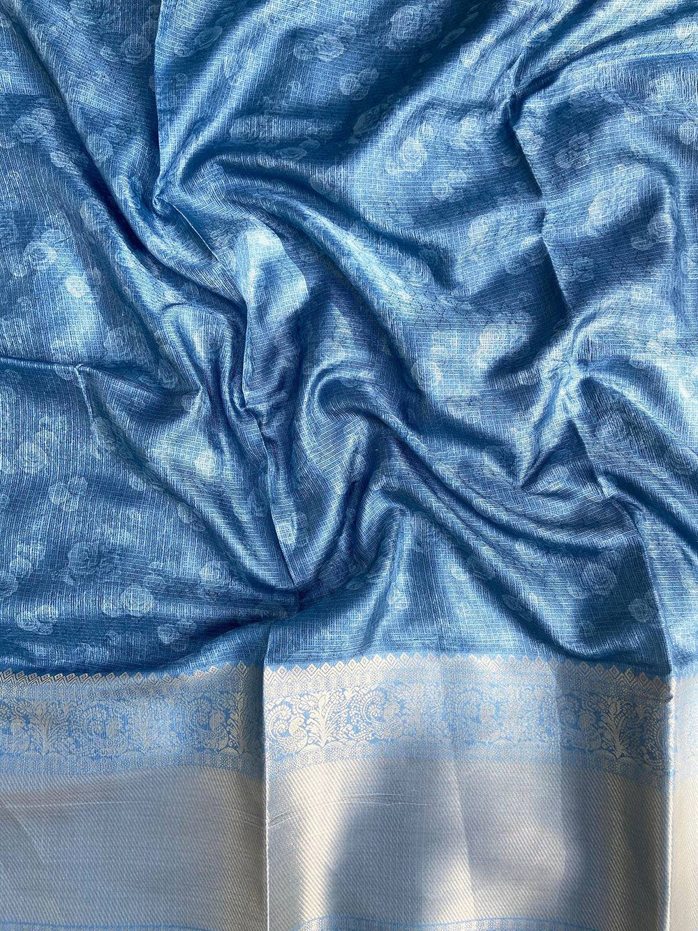 Textured blue fabric with intricate gold zari border