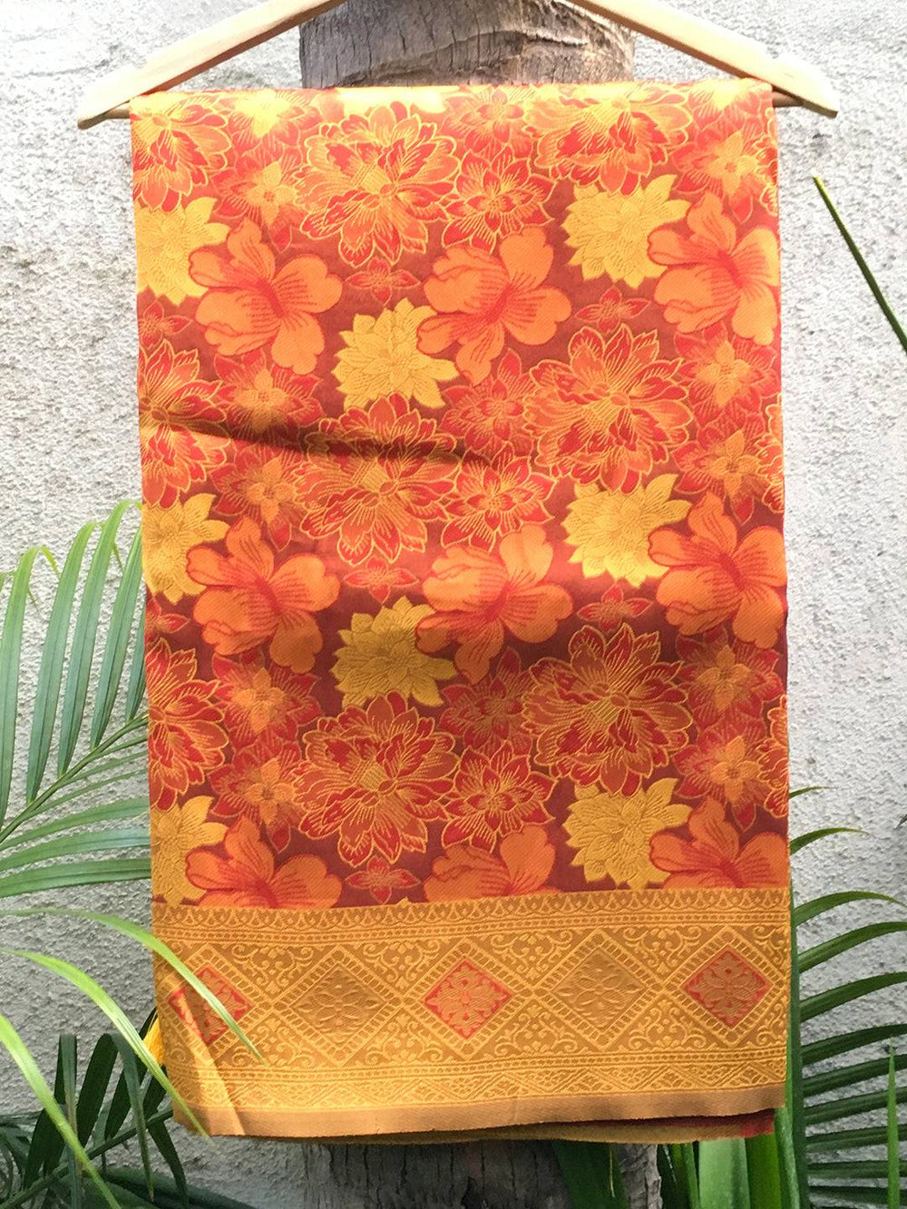 Rust silk saree with floral butta design displayed on hanger