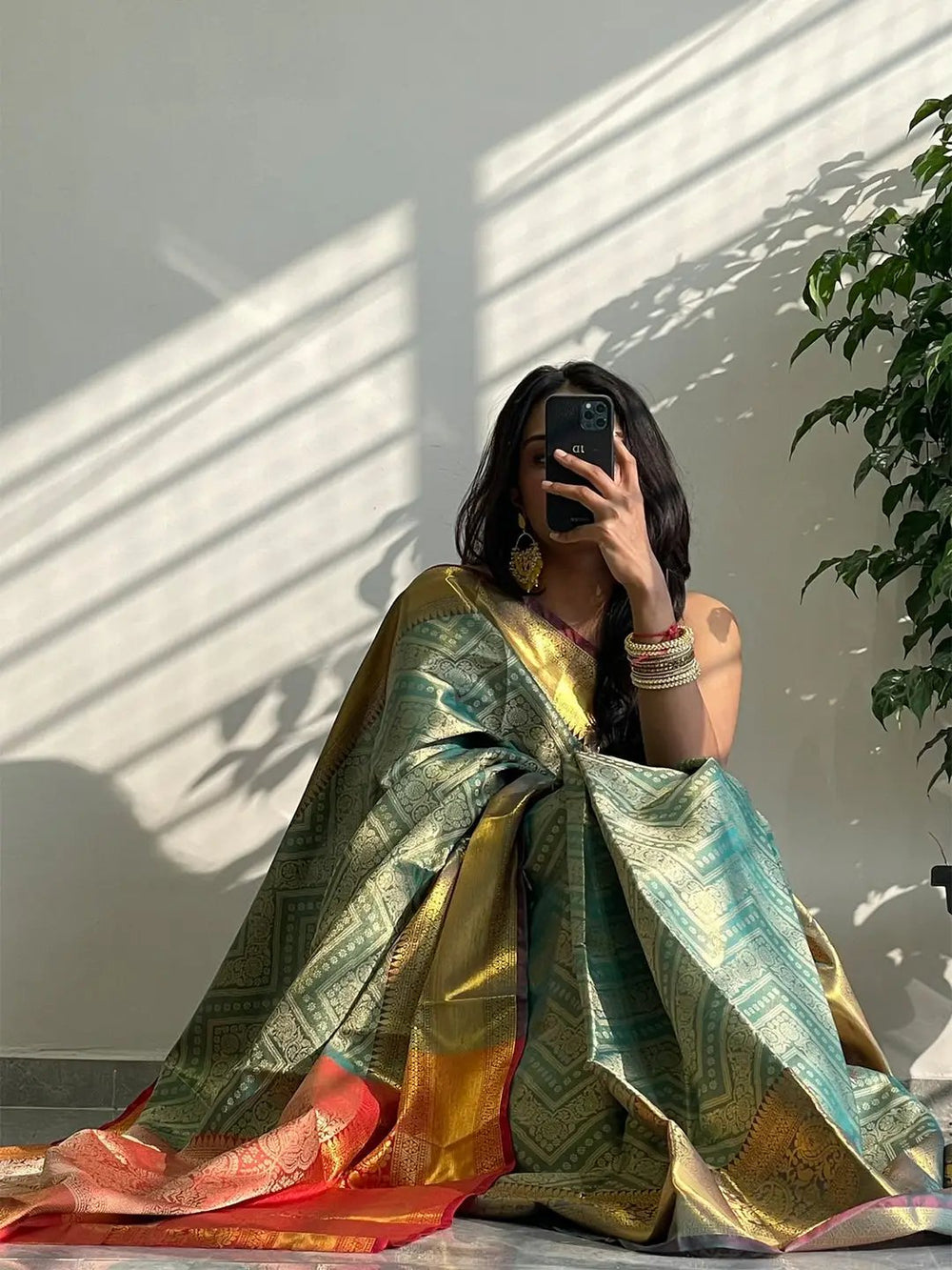Model sitting with gold zari Kanjivaaram silk saree.