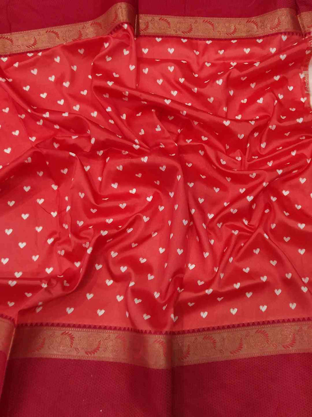 Close-up of red Gadwal border on soft silk saree with heart patterns