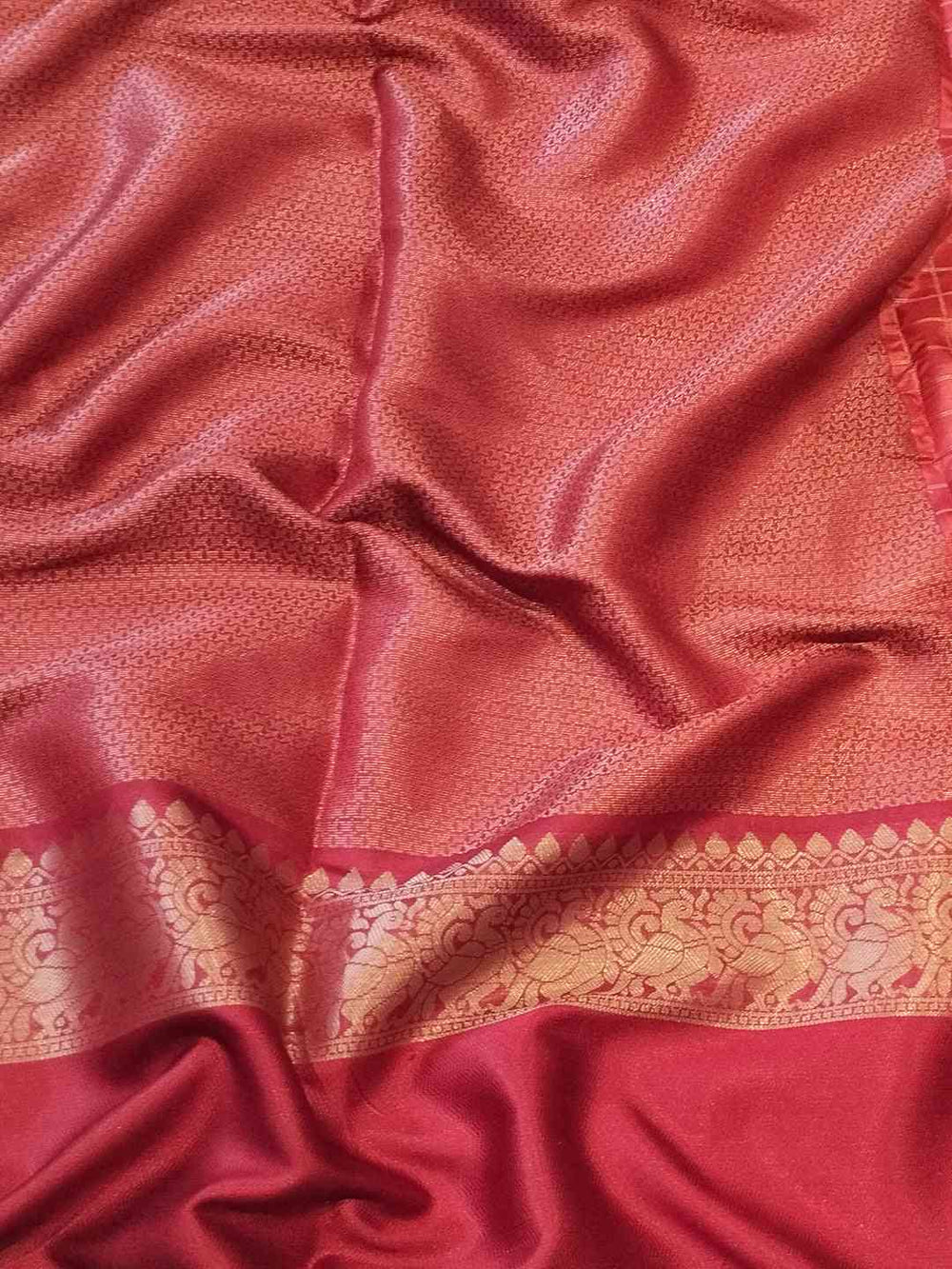 Rich red Banarasi saree fabric with intricate gold border design.