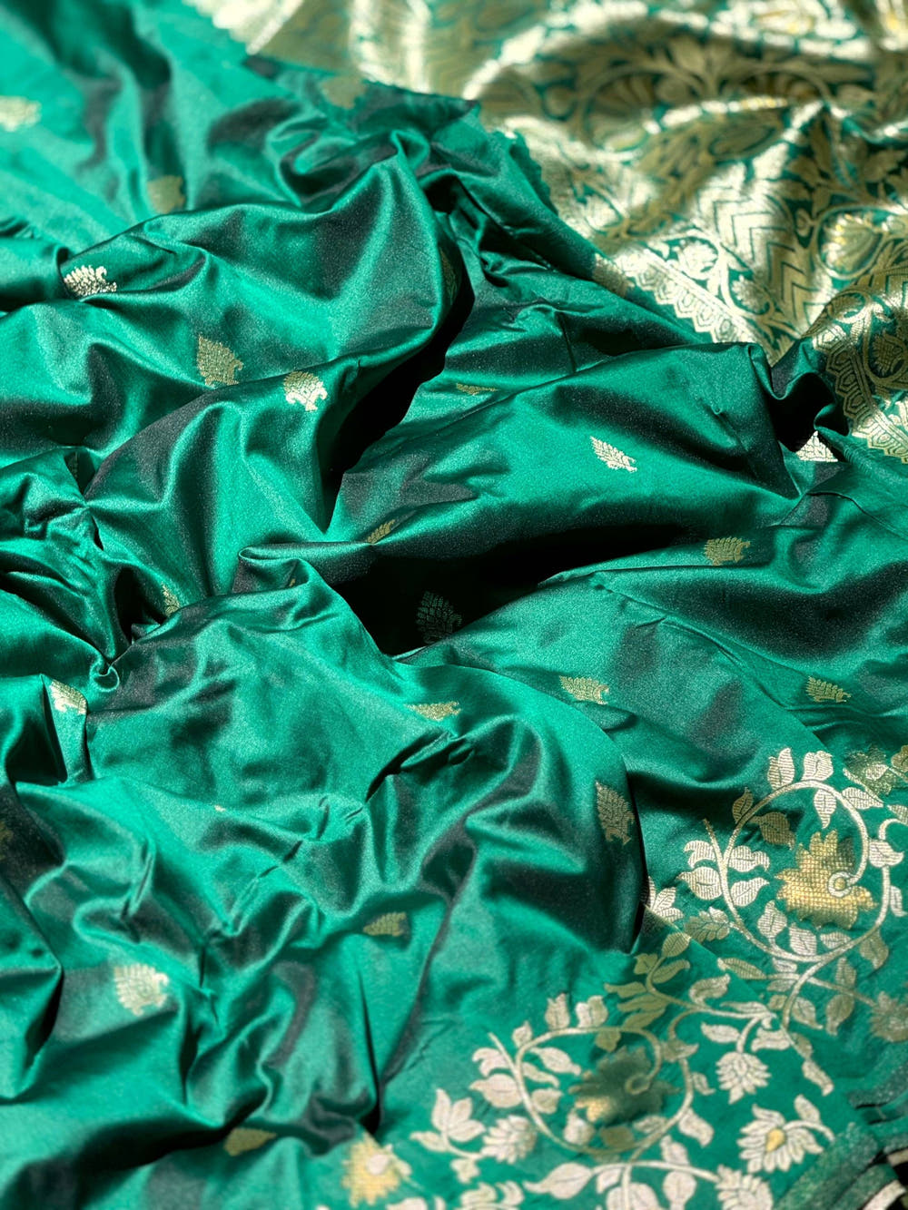 Close-up of green silk saree with intricate gold zari patterns