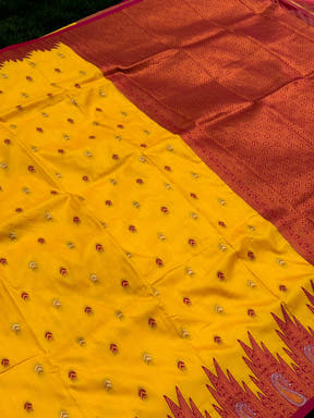 Close-up of yellow silk saree with intricate embroidery and red border