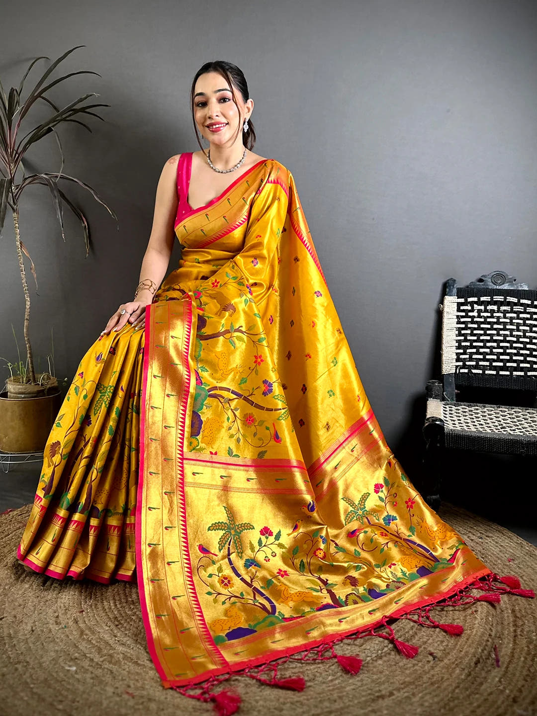 Mustard Soft Silk Paithani-style woven saree, seated pose showing the woven pallu, zari work and pink tassels