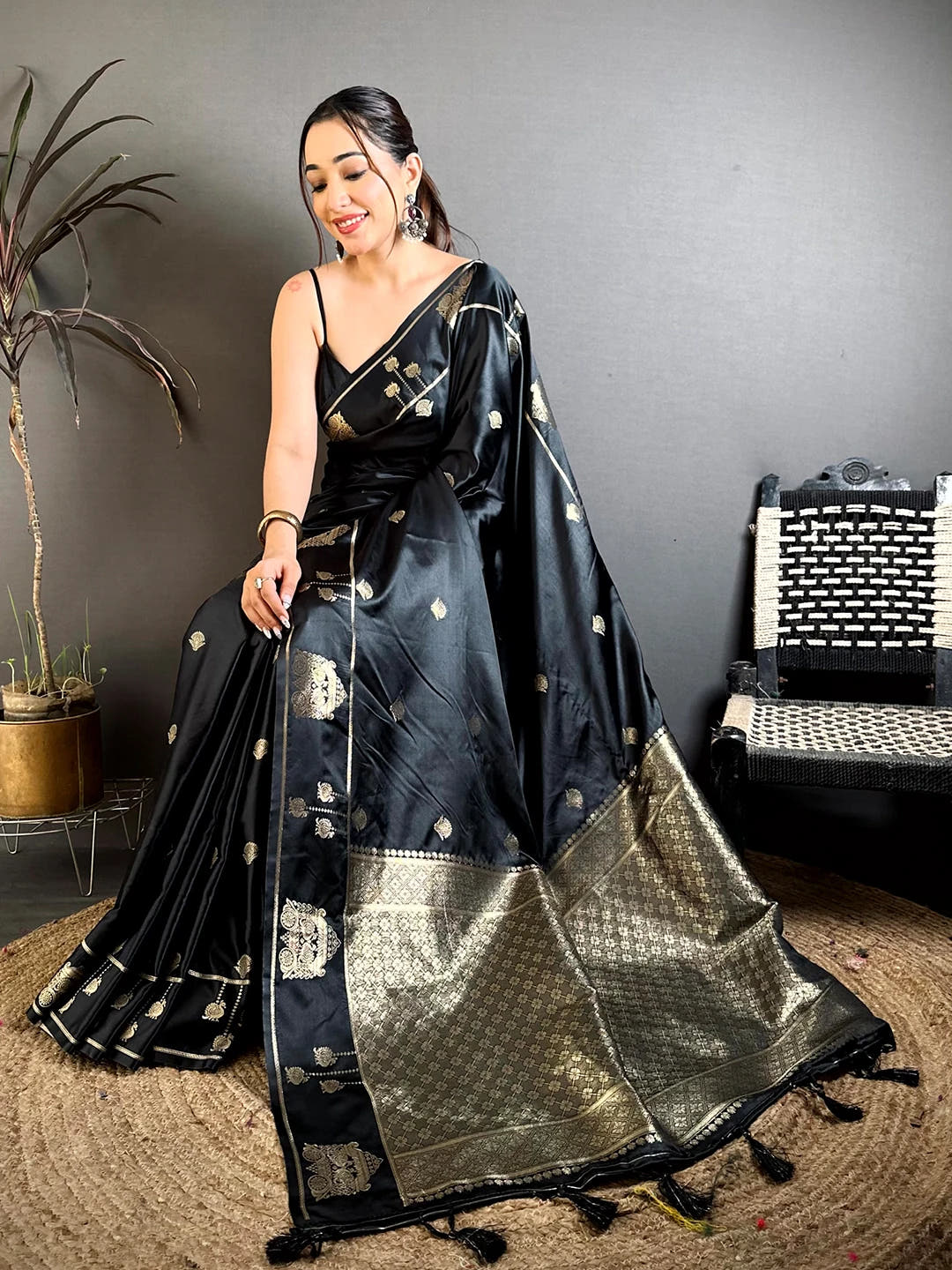 Black Mashru Satin Silk zari peacock butta saree, seated pose on model with the zari border and tassels spread on the floor