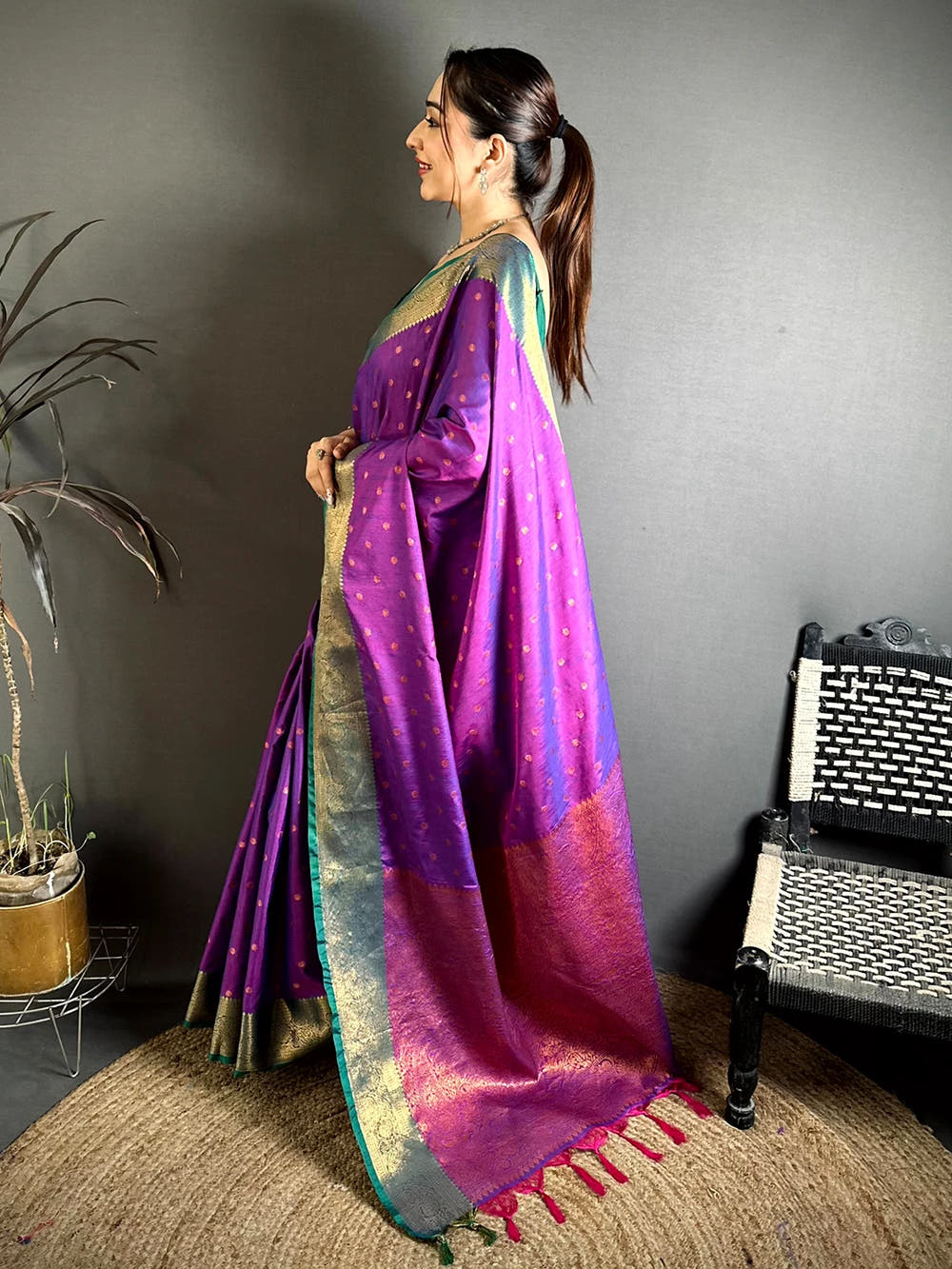 Royal purple raw silk woven buti saree, side view on model showing the woven pallu falling to the tassels