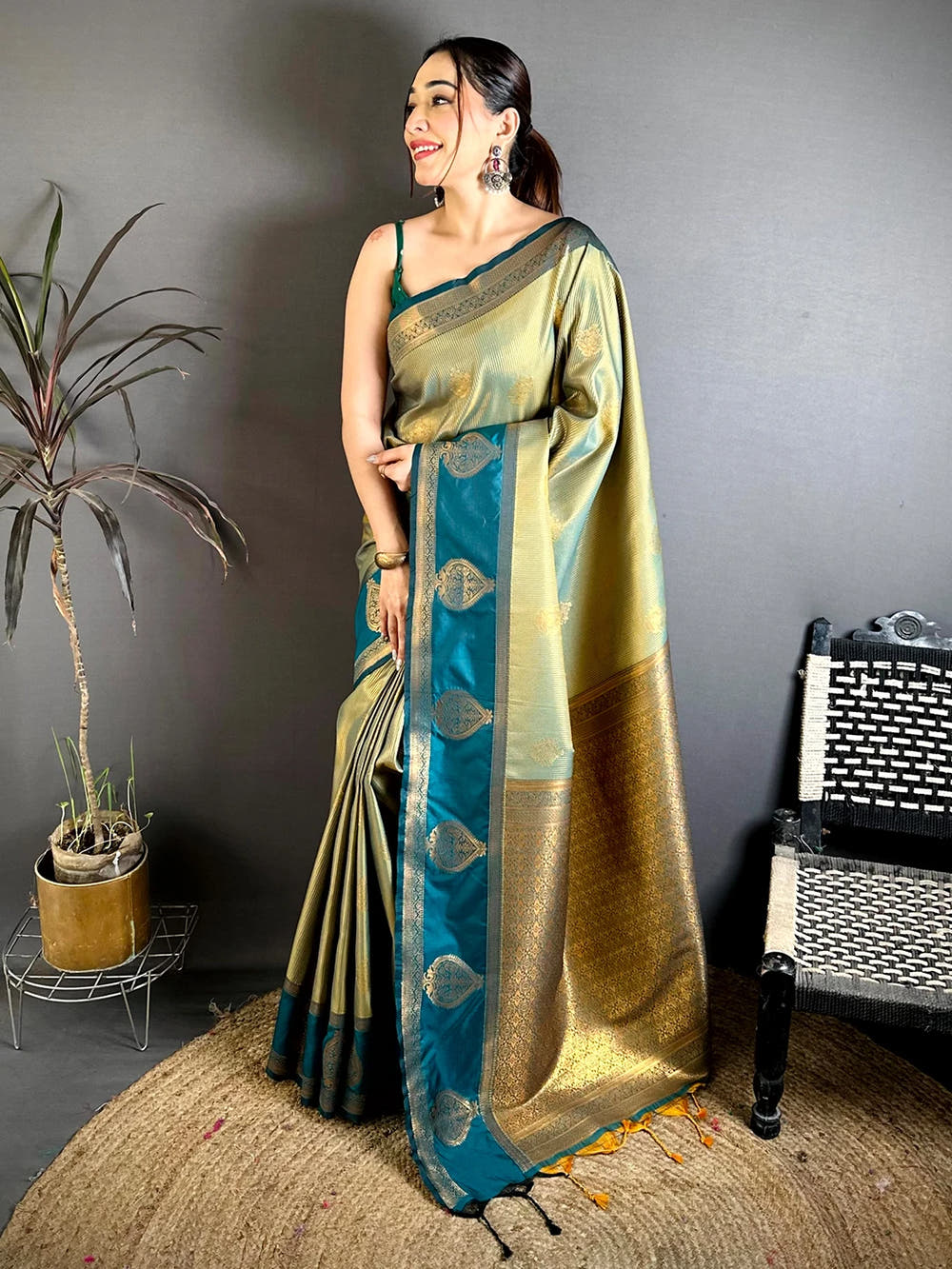 Sage green tissue zari saree with teal gadwal-style border and rich zari pallu, full standing view