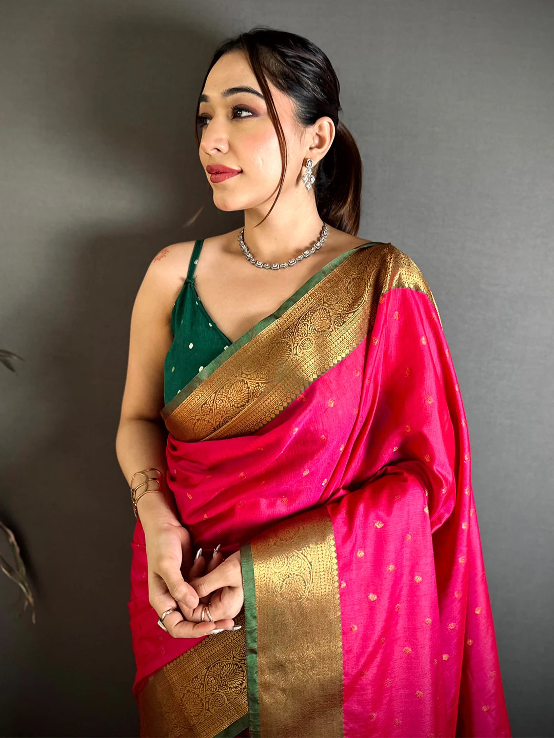 Royal Pink Raw Silk woven buti saree, front drape on a model with a green blouse and gold zari-style border