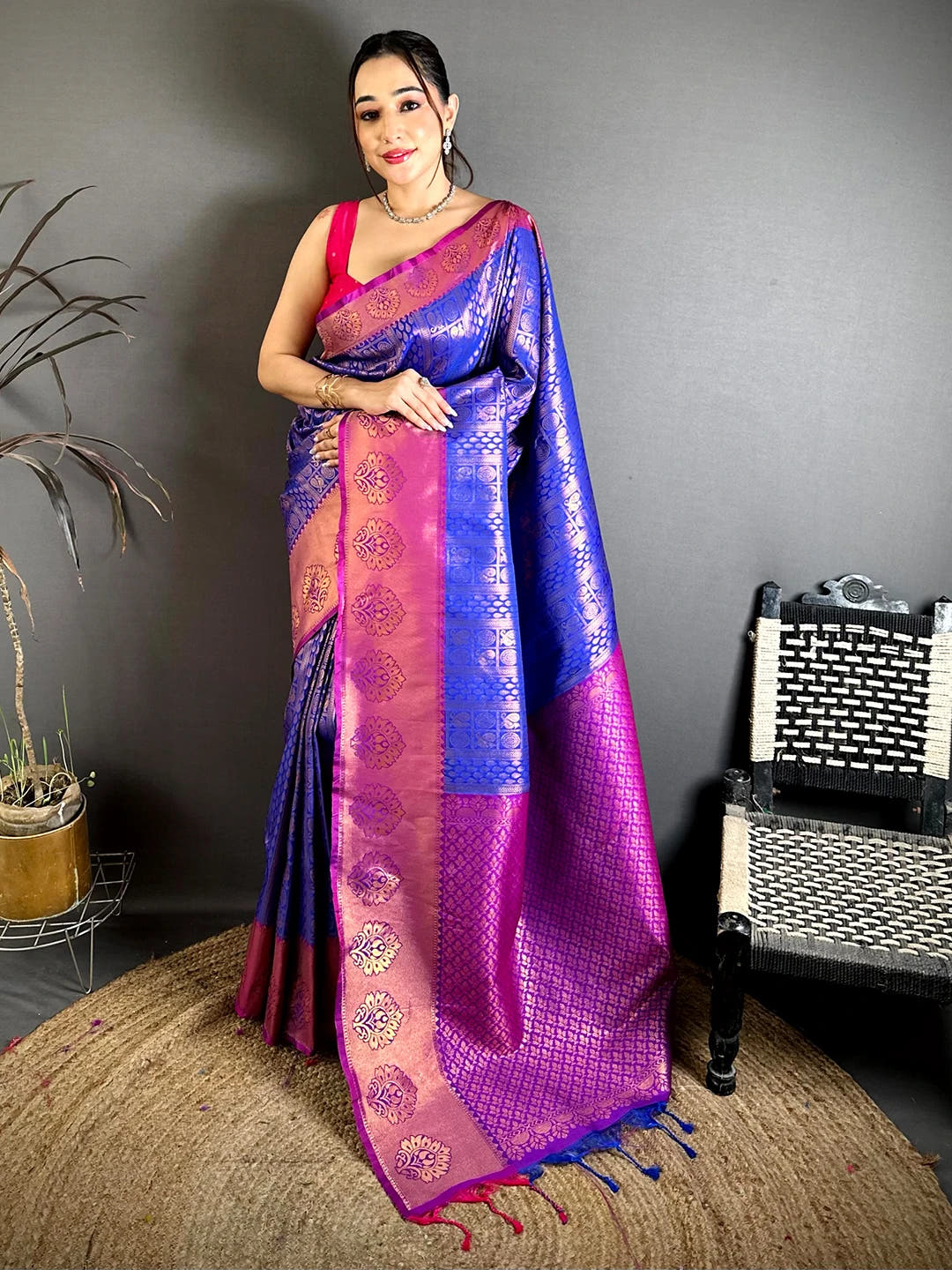 Royal blue soft silk zari woven saree, full length standing view with magenta pallu and tassels on a jute rug